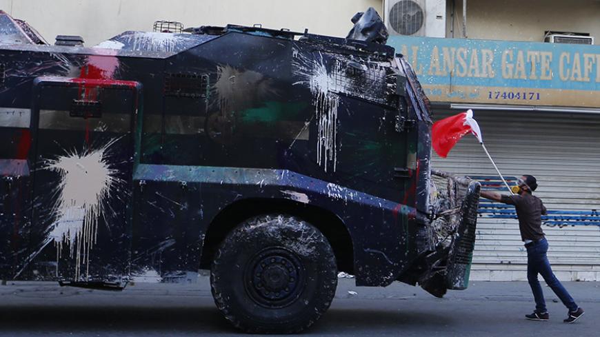 A protester, holding a Bahraini flag, confronts a riot police armoured personnel carrier in an attempt to stop it from entering the village of Bilad Al Qadeem south of Manama, January 6, 2015.
  Bahraini police fired rubber bullets and tear gas to scatter protesters who gathered outside the home of Sheikh Ali Salman, a Shi'ite Muslim opposition leader on Monday, witnesses said, after he was remanded in custody for a further 15 days. Around 100 protesters angry at the decision had assembled outside his house