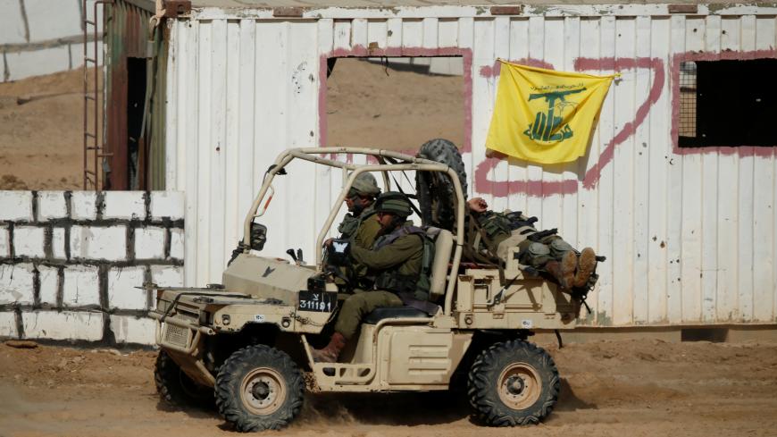 Israeli soldiers evacuate their comrade, playing the role of an injured person, as they drive past a Hezbollah flag during a combined forces drill in Shizafon military base, near Eilat in southern Israel June 7, 2016. REUTERS/Amir Cohen  - RTSGDEV