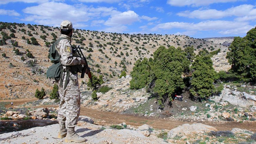 A Lebanon Hezbollah fighter carries his weapon as he stands in Khashaat, in the Qalamoun region after they advanced in the area May 15, 2015.  When Lebanon's Hezbollah first joined Syria's war on the side of President Bashar al-Assad, its role was a closely guarded secret. Today, as Hezbollah plants its flag in land won from rebels north of Damascus, its role could hardly be more public. Picture taken May 15, 2015. To match Insight MIDEAST-CRISIS/SYRIA REUTERS/Mohamed Azakir


 - RTX1DH3B