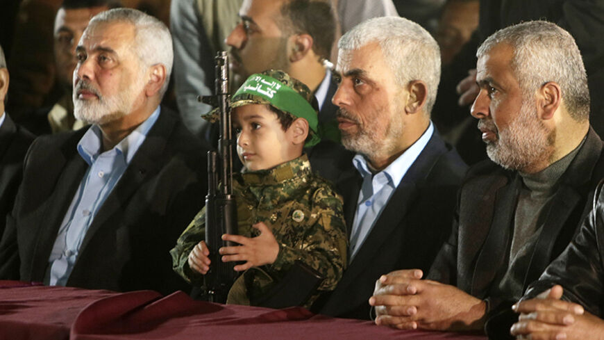 TOPSHOT - Yahya Sinwar (2nd R), the new leader of the Hamas Islamist movement in the Gaza Strip and senior political leader Ismail Haniyeh (L) sit next to the son of  Mazen Faqha, a Hamas leader who was shot dead by unknown gunmen in the Gaza Strip, during a memorial on March 27, 2017 in Gaza City. 
Hamas officials have said the killing bears the hallmarks of Israel's intelligence service Mossad, but Israel has not commented on the shooting. / AFP PHOTO / MAHMUD HAMS        (Photo credit should read MAHMUD 