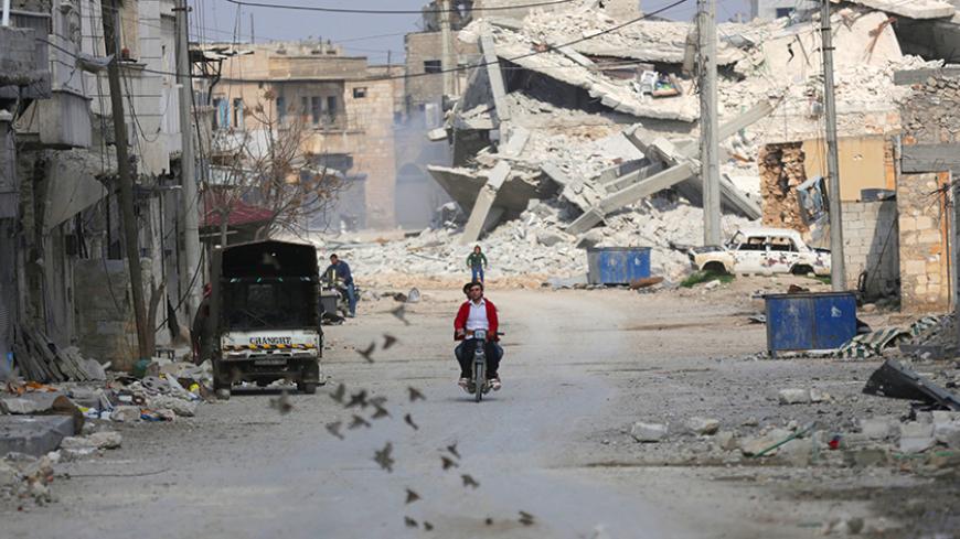 Birds fly near men riding a motorcycle through a damaged neighbourhood in the northern Syrian town of al-Bab, Syria March 4, 2017. REUTERS/Khalil Ashawi - RTS11G2W