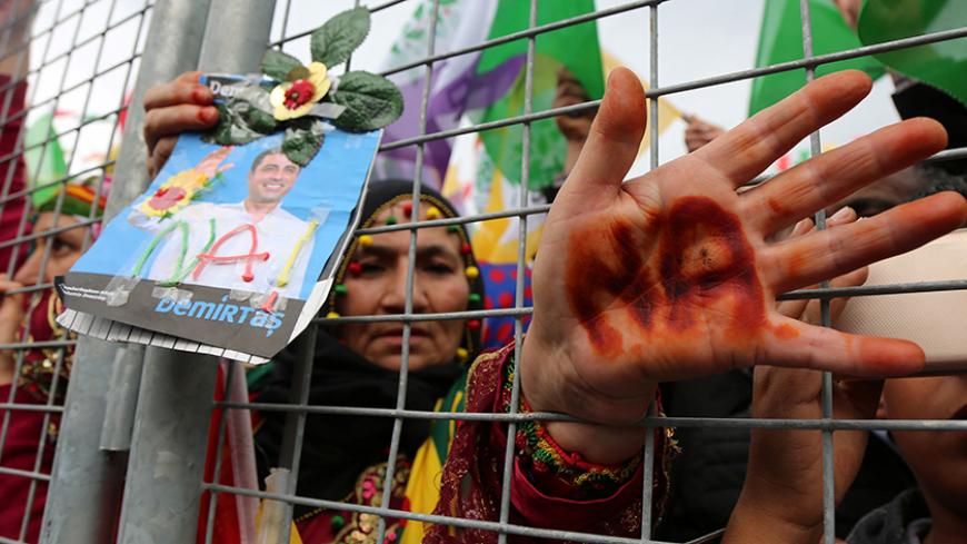 A supporter holds a portrait of Selahattin Demirtas, detained leader of Turkey's pro-Kurdish opposition Peoples' Democratic Party (HDP), and shows her hand scribbled with the Kurdish word for "No", during a rally for the upcoming referendum in the southeastern city of Diyarbakir, Turkey, April 15, 2017. REUTERS/Sertac Kayar - RTS12FFR