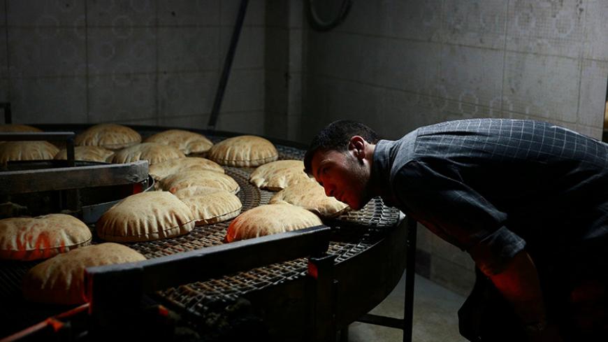 A man inspects a line of bread to be distributed as aid in the rebel held besieged city of Douma, in the eastern Damascus suburb of Ghouta, Syria April 15, 2017. Picture taken April 15, 2017. The bakery was reopened by the Unified Aid Office, which is in charge of distributing aid in eastern Ghouta, to alleviate the impact of a rise in bread prices to $2 per kg, according to the men running the bakery.  REUTERS/Bassam Khabieh     TPX IMAGES OF THE DAY - RTS12J6P