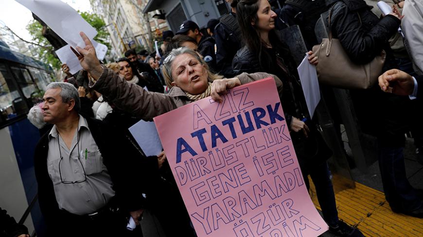 A woman holds a banner reads, "Dear Ataturk; honesty didn't work again. I am sorry" as she and other people wait in line to submit their personal appeals to the High Electoral Board for annulment of the referendum, in Ankara, Turkey, April 18, 2017. REUTERS/Umit Bektas - RTS12RUF