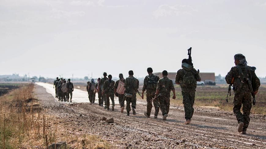 Kurdish fighters walk carrying their weapons towards Tel Abyad of Raqqa governorate after they said they took control of the area June 15, 2015. Syrian Kurdish-led forces said they had captured a town at the Turkish border from Islamic State on Monday, driving it away from the frontier in an advance backed by U.S.-led air strikes that has thrust deep into the jihadists' Syria stronghold. The capture of Tel Abyad by the Kurdish YPG and smaller Syrian rebel groups means the Syrian Kurds effectively control so
