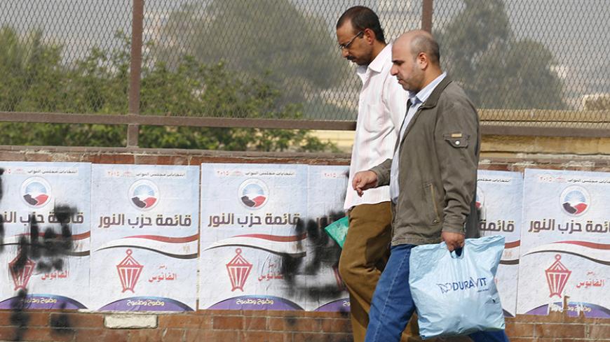 People walk in front of election campaign posters for the Salafist al-Nour Party, during the second round of parliament elections in Cairo, Egypt, November 23, 2015, on the final day of voting in Egypt's two-phase parliamentary elections. Egyptians voted on Sunday in the second phase of elections that are meant to restore parliament after a more than three-year hiatus but which critics say have been undermined by widespread repression. REUTERS/Amr Abdallah Dalsh - RTX1VE76