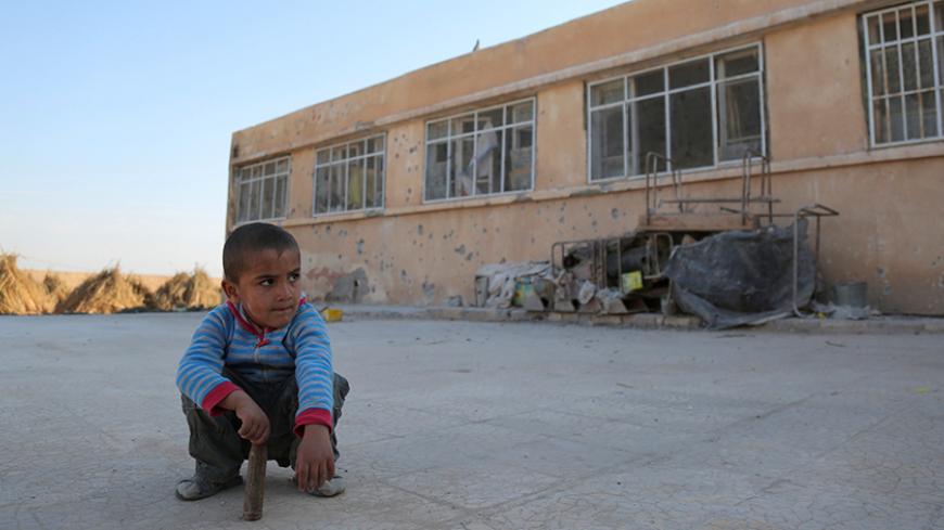 An internally displaced boy sits on the ground near a school in the village of al-Heesha in Raqqa district after it was captured from Islamic State, north of Raqqa city, Syria November 15, 2016. REUTERS/Rodi Said - RTX2TU3Q