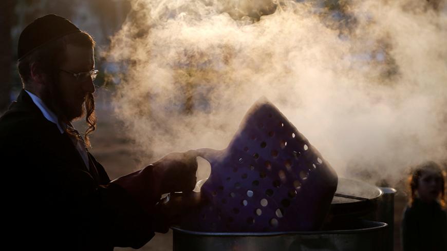 An ultra-Orthodox Jewish man dips cooking utensils in boiling water to remove remains of leaven in preparation for the Jewish holiday of Passover in the city of Ashdod April 5, 2017. REUTERS/Amir Cohen - RTX3497Q