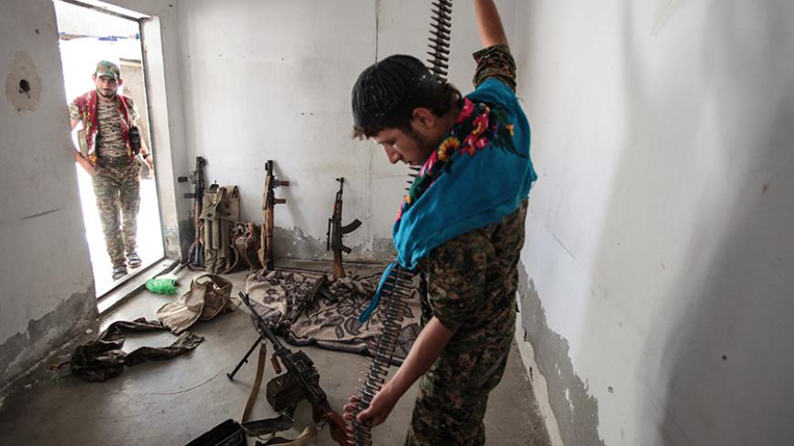 TAL ABYAD, SYRIA - JUNE 19: (TURKEY OUT) A Kurdish People's Protection Units, or YPG fighter controls the weapons in downtown of Tal Abyad, Syria. June 19, 2015. Kurdish fighters with the YPG took full control of Tal Abyad, dealing a major blow to the Islamic State group's ability to wage war in Syria. Mopping up operations have started to make the town safe for the return of residents from Turkey, after more than a year of Islamic State militants holding control of the town. (Photo by Ahmet Sik/Getty Image