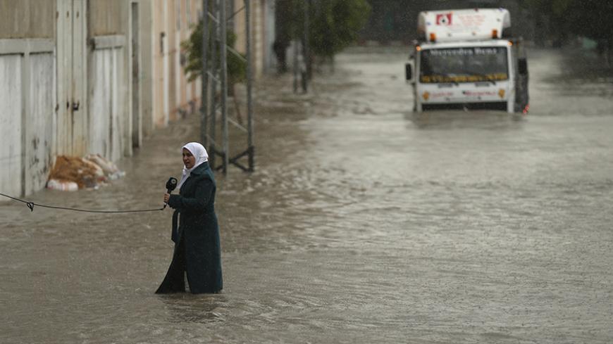 A Palestinian journalist speaks to the camera as she stands on a flooded street following heavy rain in Gaza City November 27, 2014. The civil defence asked residents in an area east of Gaza City to evacuate their homes to avoid being trapped in flood waters from a nearby lake. REUTERS/Mohammed Salem (GAZA - Tags: SOCIETY ENVIRONMENT MEDIA TPX IMAGES OF THE DAY) - RTR4FST8