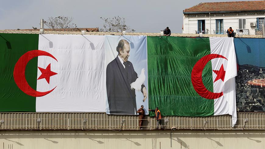 Algerian city employees install Algerian flags and President's Abdelaziz Bouteflika poster  on the streets ahead of the Parliamentary election in Algiers, Algeria April 26,2017.Picture taken 26 April 2017. REUTERS/Ramzi Boudina - RTS14O6W
