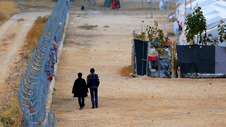 Two Syrian refugees walk along fences in Nizip refugee camp, near the Turkish-Syrian border in Gaziantep province, Turkey, November 30, 2016. REUTERS/Umit Bektas - RTSU1PW