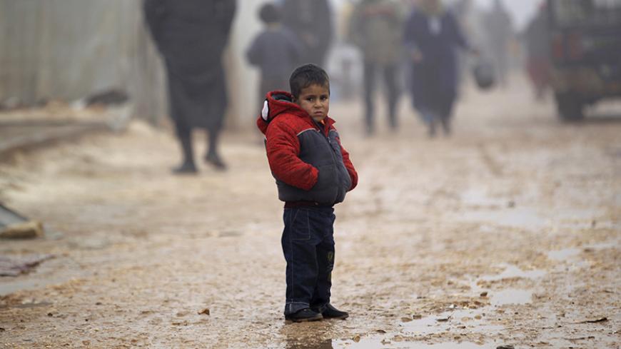 A boy stands outside tents housing internally displaced people, during the cold weather in Jerjnaz camp, in Idlib province, Syria, January 5, 2016. REUTERS/Khalil Ashawi - RTX21508