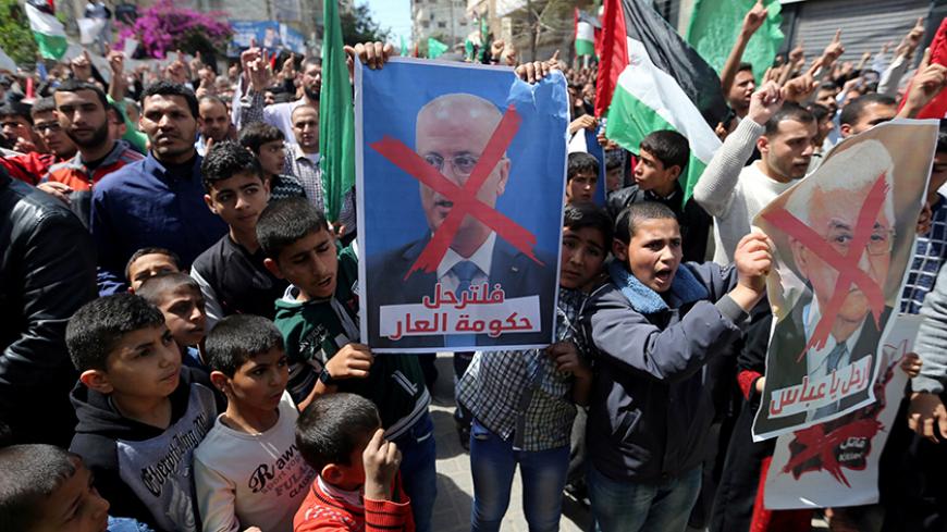 Hamas supporters hold crossed posters depicting Palestinian President Mahmoud Abbas and Palestinian Prime Minister Rami Hamdallah during a protest against them in Khan Younis in the southern Gaza Strip April 14, 2017. REUTERS/Ibraheem Abu Mustafa - RTX35K1R