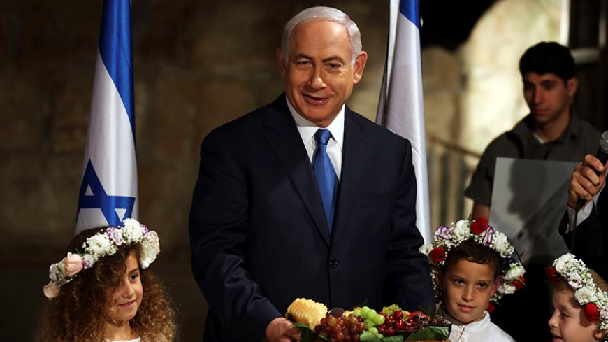 Israeli Prime Minister Benjamin Netanyahu holds a basket of fruit he received from local children, a custom associated with the upcoming Jewish holiday of Shavuot during a special cabinet meeting held in the Western Wall tunnels in Jerusalem's Old City May 28, 2017. REUTERS/Gali Tibbon/Pool - RTX37YH8