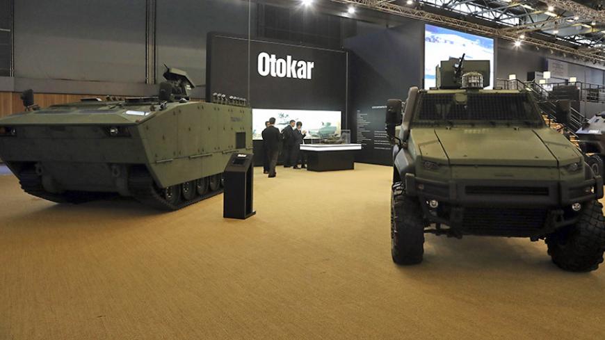 People stand near by military vehicles displayed by Turkish company Otokar on June 13, 2016 during the the Eurosatory defence and security international exhibition in Villepinte, near Paris. / AFP / Jacques DEMARTHON        (Photo credit should read JACQUES DEMARTHON/AFP/Getty Images)