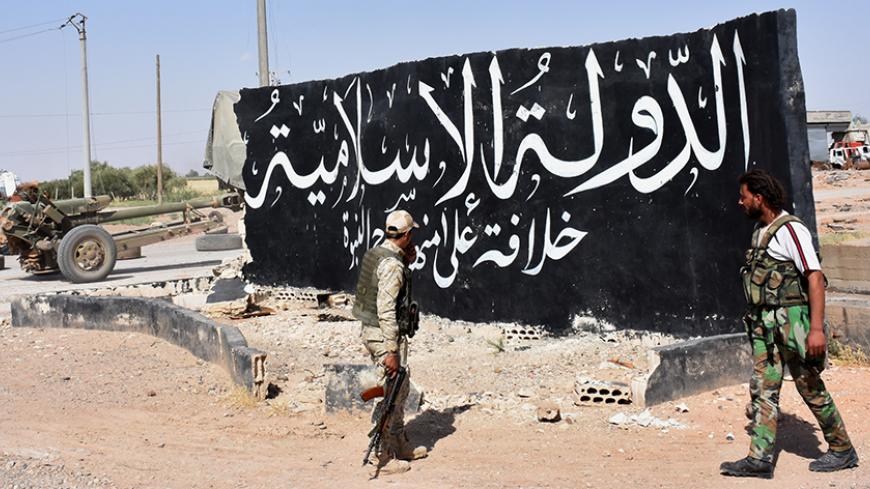 Syrian pro-government forces set up a road checkpoint next to a mural reading the Arabic: "Islamic State" after they took control of the northern Syrian town of Maskanah from the jihadists on June 5, 2017.  / AFP PHOTO / George OURFALIAN        (Photo credit should read GEORGE OURFALIAN/AFP/Getty Images)