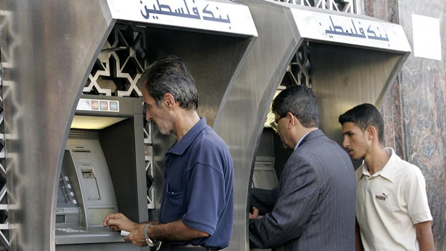 Palestinians use automated teller machines (ATMs) of the Bank of Palestine in Gaza September 25, 2007. Bank Hapoalim, Israel's biggest commercial bank, said on Tuesday it was severing its business ties with Palestinian banks in the Gaza Strip in response to the Israeli government's classification of the territory as an enemy entity. REUTERS/Ibraheem Abu Mustafa (GAZA) - RTR1U8N4
