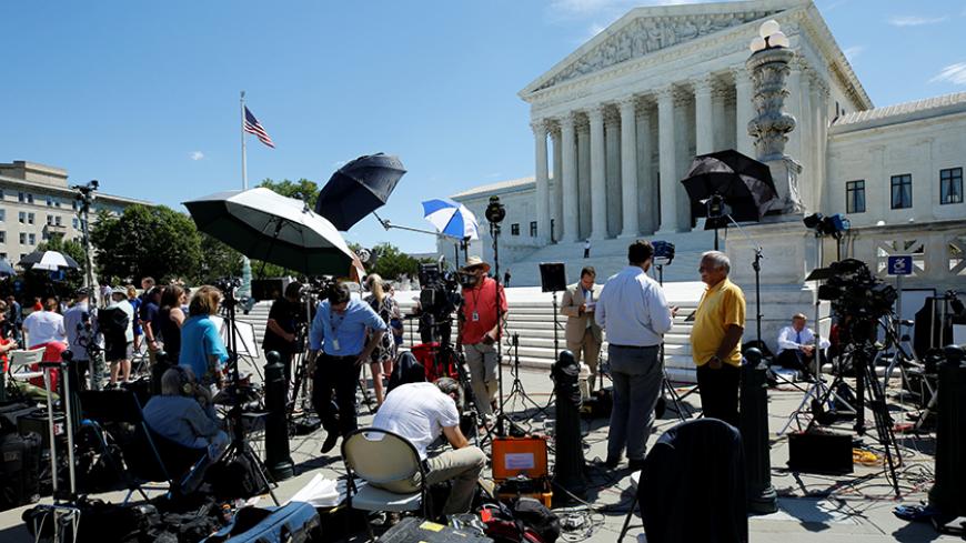 Reporters wait outside the U.S. Supreme Court before it granted parts of the Trump administration's emergency request to put his travel ban into effect immediately while the legal battle continues, in Washington, U.S., June 26, 2017. REUTERS/Yuri Gripas - RTS18PDP