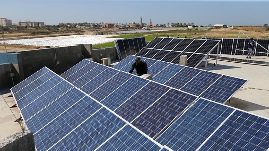 A Palestinian worker installs solar panels atop the roof of a medical centre in Gaza City March 1, 2016. REUTERS/Ibraheem Abu Mustafa - RTS9Z0H