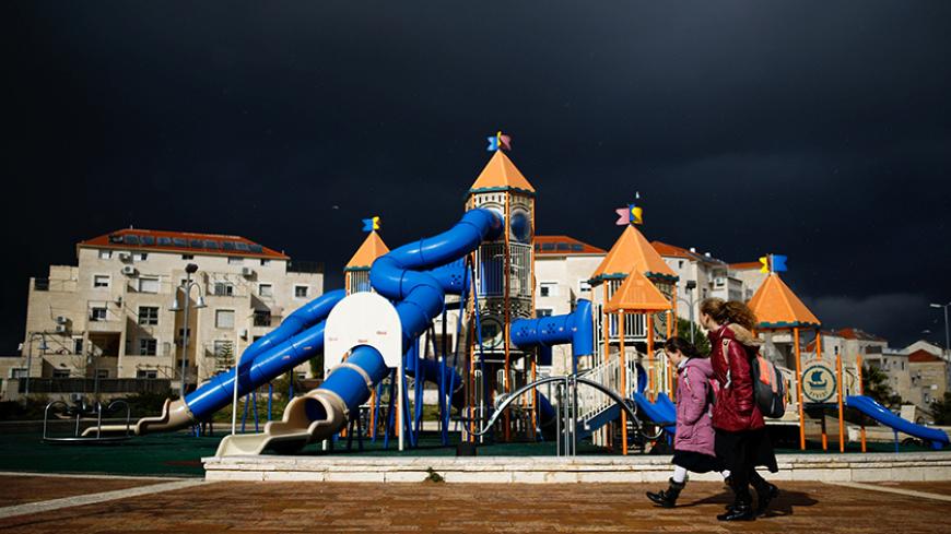 Girls walk in a playground on a stormy day in the Israeli settlement of Beitar Illit in the occupied West Bank February 15, 2017. REUTERS/Amir Cohen - RTSYSC1