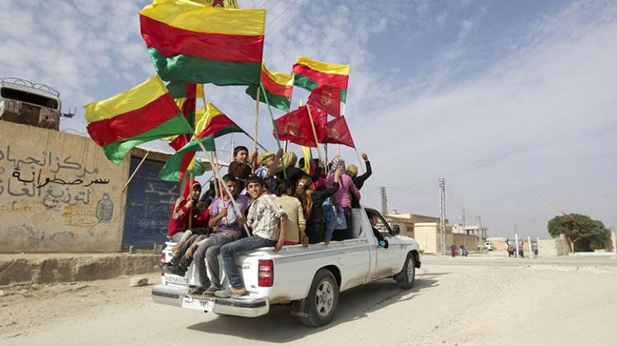 People sit in the back of a truck as they celebrate what they said was the liberation of villages from Islamist rebels near the city of Ras al-Ain in the province of Hasakah, after capturing it from Islamist rebels November 6, 2013. Redur Xelil, spokesman for the armed wing of the Syrian Kurdish Democratic Union Party (PYD), said Kurdish militias had seized the city of Ras al-Ain and all its surrounding villages. Syrian Kurdish fighters have captured more territory from Islamist rebels in northeastern Syria