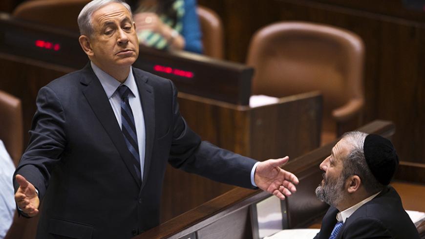 Israeli Prime Minister Benjamin Netanyahu (L) gestures as he speaks to incoming minister Aryeh Deri, party leader of the Ultra-Orthodox Shas party, in the Knesset, the Israeli parliament, in Jerusalem May 13, 2015. Netanyahu's emerging government scraped by its first parliamentary test on Wednesday, paving the way for the new cabinet to be sworn in after two months of difficult coalition building. REUTERS/Ronen Zvulun       TPX IMAGES OF THE DAY      - RTX1CSJH