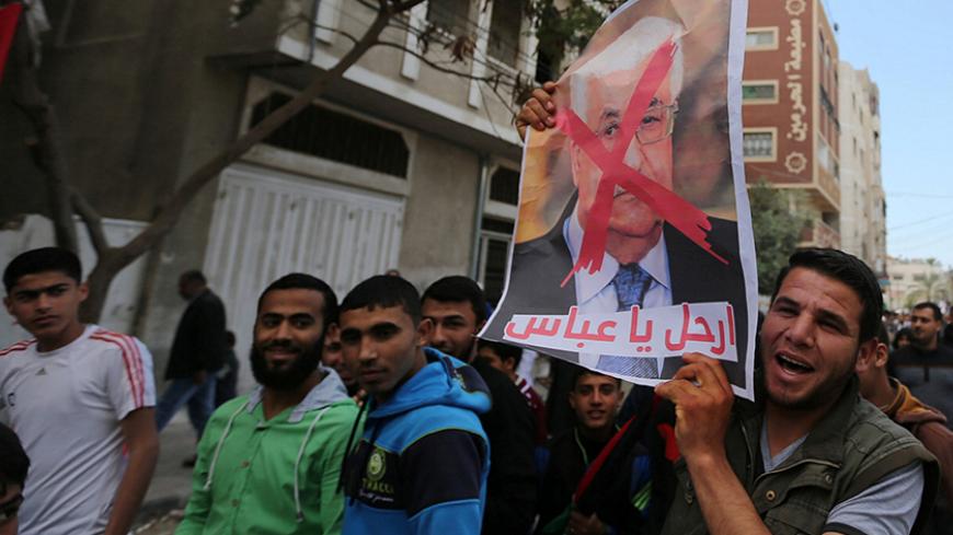 A Hamas supporter holds a crossed poster depicting Palestinian President Mahmoud Abbas during a protest against Abbas and Palestinian Prime Minister Rami Hamdallah in Khan Younis in the southern Gaza Strip April 14, 2017. REUTERS/Ibraheem Abu Mustafa - RTX35K2I