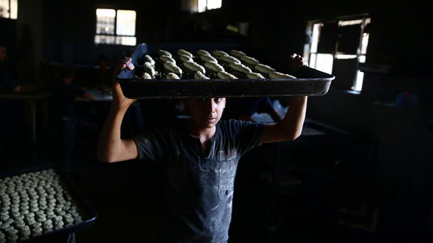 A boy carries raw pastries prior to baking, to be sold during Ramadan in the rebel held besieged eastern Damascus suburb of Ghouta, Syria May 28, 2017. REUTERS/Bassam Khabieh - RTX380FD
