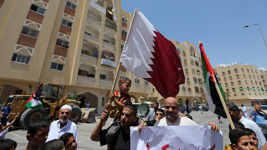 A Palestinian man and his son hold a Qatari flag during a rally in support of Qatar, inside Qatari-funded construction project 'Hamad City', in the southern Gaza Strip June 9, 2017. REUTERS/Ibraheem Abu Mustafa - RTX39TEW