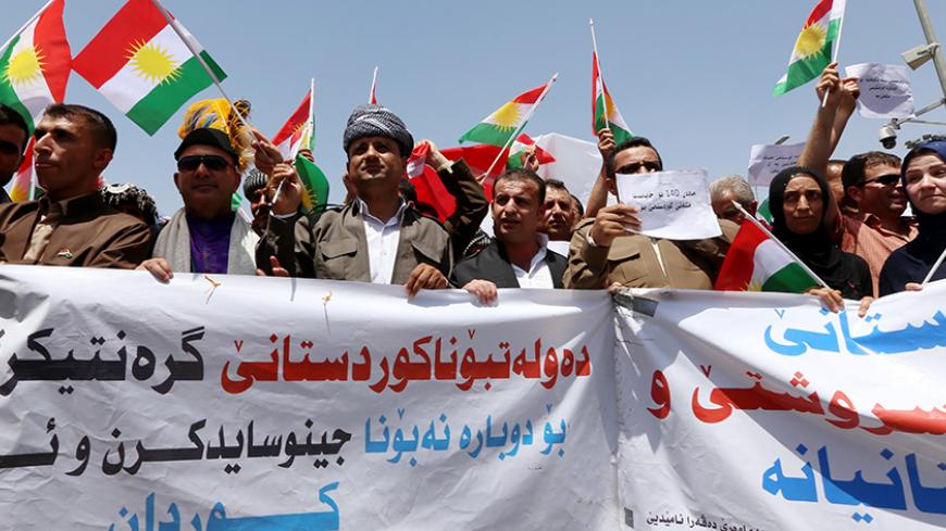 Iraqi Kurdish protesters hold a banner and wave flags of their autonomous Kurdistan region during a demonstration to claim for its independence on July 3, 2014 outside the Kurdistan parliament building in Arbil, in northern Iraq. The Kurdish leader, Massud Barzani asked its parliament to start organizing a referendum on independence.  AFP PHOTO / SAFIN HAMED        (Photo credit should read SAFIN HAMED/AFP/Getty Images)
