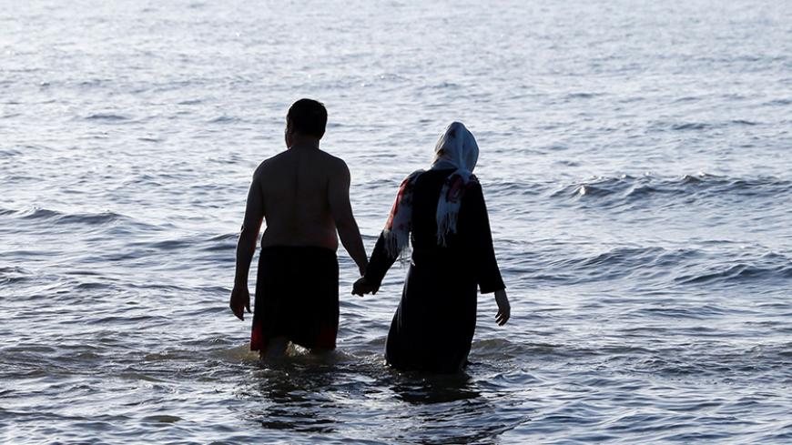 An Iranian couple walks in the sea in the Caspian Sea port city of Mahmoud Abad, in northern Mazandaran province on June 16, 2016.
 / AFP / ATTA KENARE        (Photo credit should read ATTA KENARE/AFP/Getty Images)