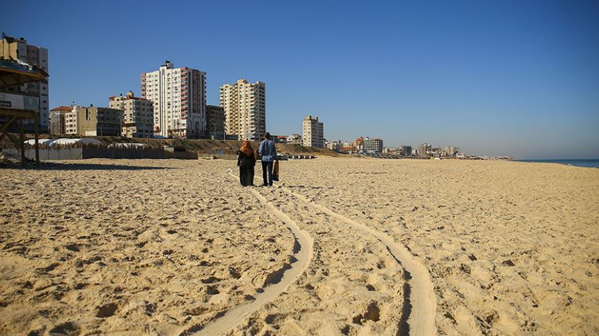 TOPSHOT - A Palestinian couple walk along traces of cart tracks on a beach in Gaza City on June 7, 2017. / AFP PHOTO / MOHAMMED ABED        (Photo credit should read MOHAMMED ABED/AFP/Getty Images)