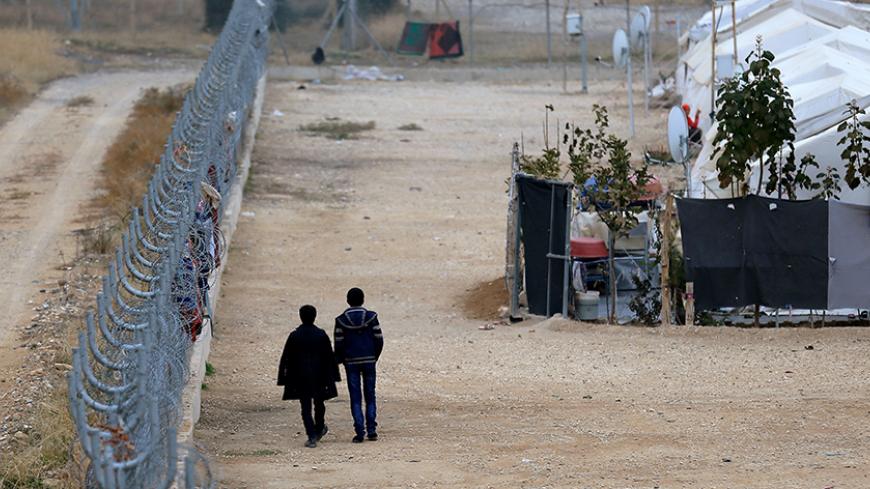 Two Syrian refugees walk along fences in Nizip refugee camp, near the Turkish-Syrian border in Gaziantep province, Turkey, November 30, 2016. REUTERS/Umit Bektas - RTSU1PW