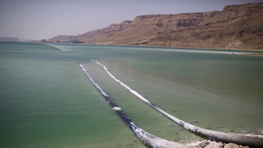 Pipes that pump water cross through evaporation pools, which today make up the southern part of the Dead Sea, Israel July 27, 2015. The Dead Sea is shrinking, and as its waters vanish at a rate of more than one meter a year, hundreds of sinkholes, some the size of a basketball court, some two storeys deep, are devouring land where the shoreline once stood.Picture taken July 27, 2015. REUTERS/Amir Cohen - RTX1M941