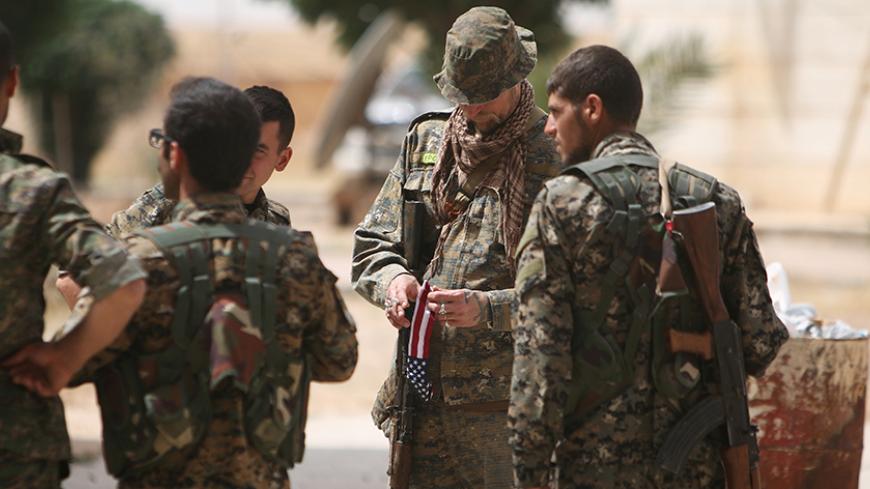 A U.S. fighter, who is fighting alongside with Syria Democratic Forces (SDF), carries his national flag as he stands with SDF fighters in northern province of Raqqa, Syria May 27, 2016. REUTERS/Rodi Said - RTX2EIZN
