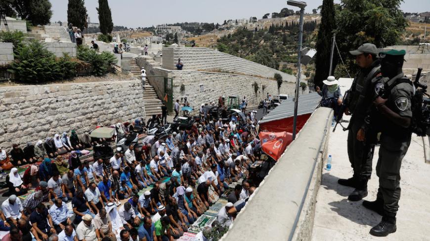 Israeli border police officers stand guard as Palestinians pray at Lions' Gate, the entrance to Jerusalem's Old City, in protest over Israel's new security measures at the compound housing al-Aqsa mosque, known to Muslims as Noble Sanctuary and to Jews as Temple Mount July 20, 2017. REUTERS/Ronen Zvulun - RTX3C773