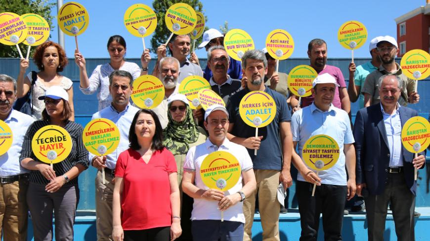 Pro-Kurdish opposition Peoples' Democratic Party (HDP) lawmakers hold placards in Kurdish and Turkish during a protest against a state crackdown, which has seen dozens of lawmakers and mayors jailed over suspected links to militant separatists, in Diyarbakir, Turkey July 26, 2017. REUTERS/Sertac Kayar - RTX3CYCO