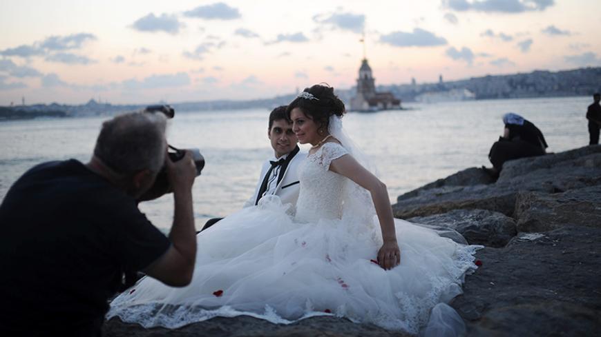 A newly married couple poses for their wedding pictures in front of The Maiden's Tower (background), on August 20, 2013 in Istanbul. The Maiden's Tower, also known as Leander's Tower, stands on a small islet located at the southern entrance of the Bosphorus strait 200 m (220 yd) from the coast of Usk?dar. AFP PHOTO/BULENT KILIC        (Photo credit should read BULENT KILIC/AFP/Getty Images)