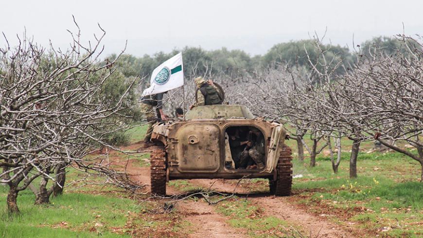 A picture taken on March 22, 2017 near the town of Maardes in the countryside of the central Syrian province of Hama, shows an armoured vehicle carrying rebel fighters, and bearing the flag of the Tahrir al-Sham rebel alliance. / AFP PHOTO / Omar haj kadour        (Photo credit should read OMAR HAJ KADOUR/AFP/Getty Images)