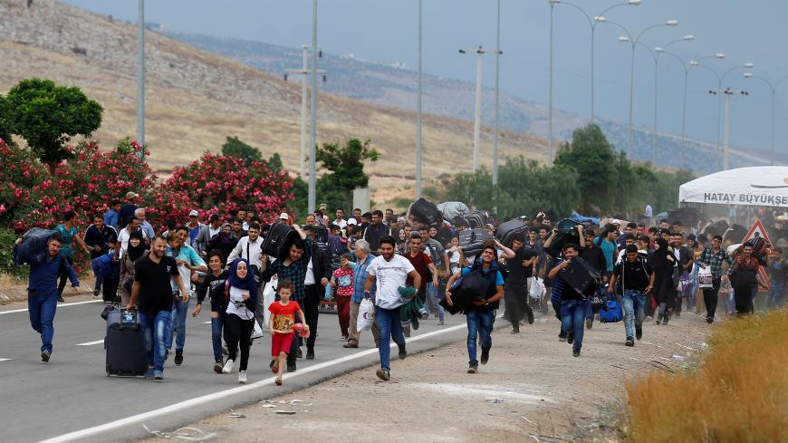 Syrians, who say they are returning to Syria ahead of Eid al-Fitr, carry their belongings as they walk to the Turkish Cilvegozu border gate located opposite of the Syrian crossing point of Bab al-Hawa in Reyhanli, in the southern Hatay province, Turkey June 14, 2017. REUTERS/Umit Bektas - RTS174AK