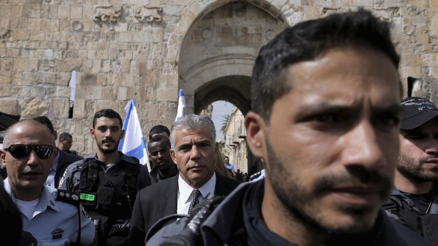 Yair Lapid (C), leader of the centrist Yesh Atid party, is surrounded by police as he visits the scene of what Israeli police said was a  stabbing attack outside the Lion's Gate of Jerusalem's Old City October 12, 2015. A border policeman shot dead a Palestinian who police said tried to stab him, according to Israeli police. The account was disputed by a Palestinian passerby, who said he witnessed the incident and saw no knife. REUTERS/Ammar Awad  - RTS449S