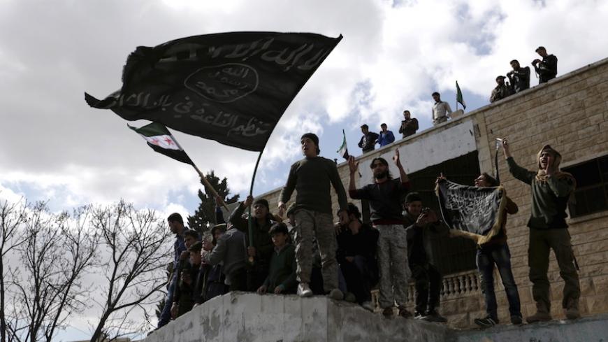 Protesters carry Al-Qaeda flags during an anti-government protest after Friday prayers in the town of Marat Numan in Idlib province, Syria, March 11, 2016. REUTERS/Khalil Ashawi - RTSAD3X