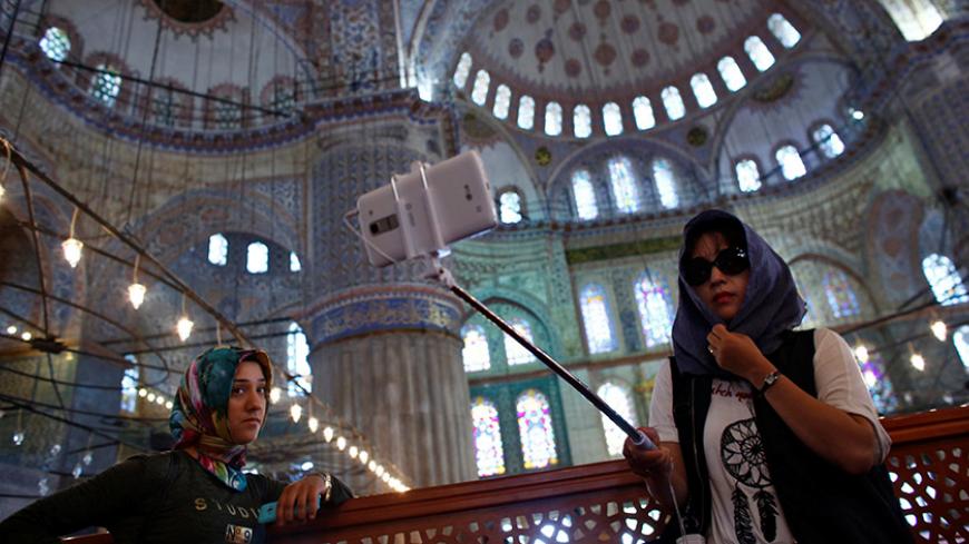 A South Korean tourist (R) takes a selfie as she visits the Ottoman-era Sultanahmet mosque, also known as the Blue Mosque, in Istanbul, Turkey, June 10, 2016. REUTERS/Murad Sezer - RTSGWZG