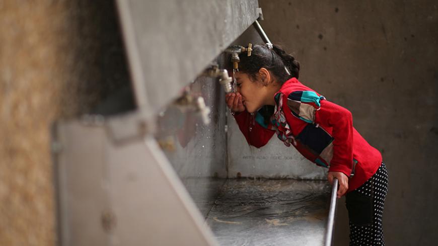 A Palestinian girl drinks water from a public tap in Jabaliya refugee camp in the northern Gaza Strip January 24, 2017. Picture taken January 24, 2017. REUTERS/Mohammed Salem - RTSXG9O