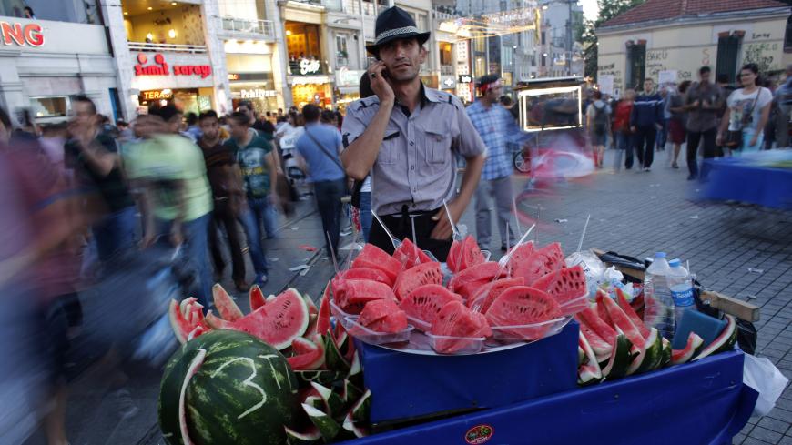 A street vendor selling watermelons talks on his mobile phone as he waits for customers at Taksim square in central Istanbul June 9, 2013. Turkish Prime Minister Tayyip Erdogan rallied his supporters in a string of defiant speeches on Sunday as tens of thousands of anti-government demonstrators massed in Istanbul's central Taksim Square.  REUTERS/Murad Sezer (TURKEY - Tags: POLITICS SOCIETY CIVIL UNREST) - RTX10HOC
