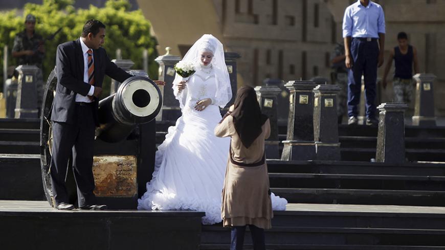 A bride and groom have their photos taken in front of the tomb of late Egyptian President Anwar al-Sadat and the Unknown Soldier monument, near a pro-Mursi protest camp in Rabaa Adawiya Square in Nasr City, east of Cairo August 11, 2013. REUTERS/Amr Abdallah Dalsh (EGYPT - Tags: POLITICS SOCIETY) - RTX12HG5