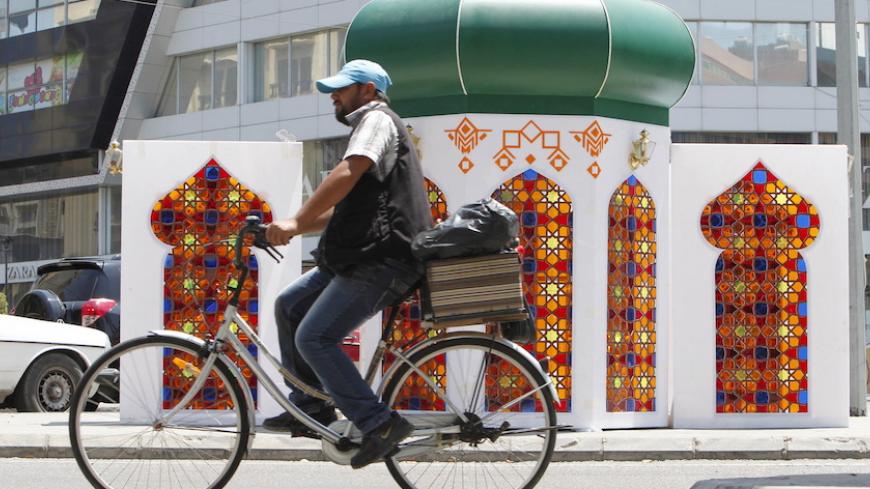 A man rides a bicycle near decorations erected ahead of the holy fasting month of Ramadan at the port city of Sidon, southern Lebanon, June 16, 2015. REUTERS/Ali Hashisho - RTX1GRZD