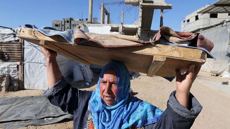 A Palestinian woman carries bread to be baked, near the wreckage of her house that witnesses said was destroyed by Israeli shelling during a 50-day war last summer, in Khan Younis in the southern Gaza Strip June 22, 2015. Israel disputed on Monday the findings of a U.N. report that it may have committed war crimes in the 2014 Gaza conflict, saying its forces acted "according to the highest international standards". There was no immediate comment from Hamas, the dominant Palestinian movement in the Gaza Stri