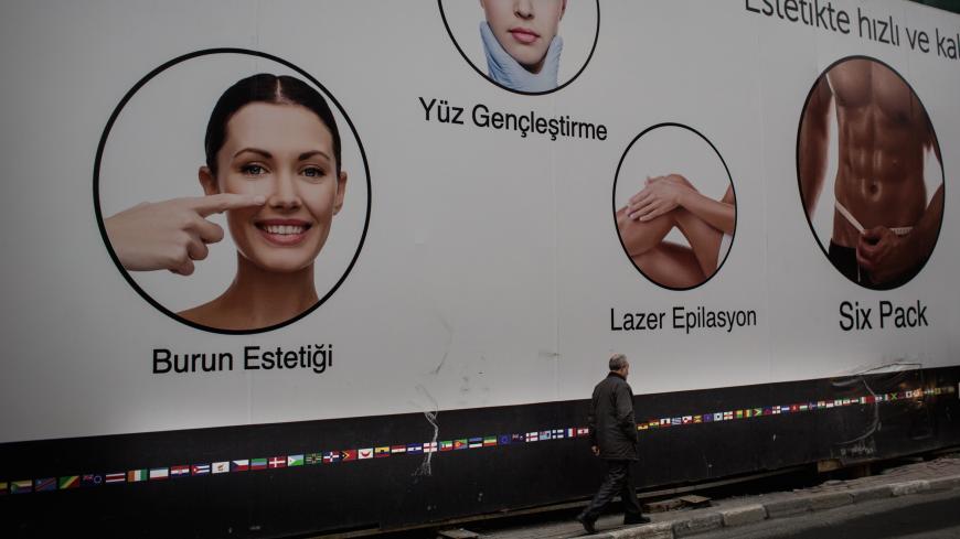 ISTANBUL, TURKEY - FEBRUARY 15: A man walks past a billboard promoting medical treatments at the luxury Esteworld Clinic on February 15, 2017 in Istanbul, Turkey. Esteworld clinic is one of many Turkish run health clinics tailoring vacation packages to tourists wishing to undergo specific medical surgeries, generally offering a three day hotel deal with airport transfers, sightseeing, meals and the surgery. The company provides health tourism to clients in more than 100 countries and has seen business boom 